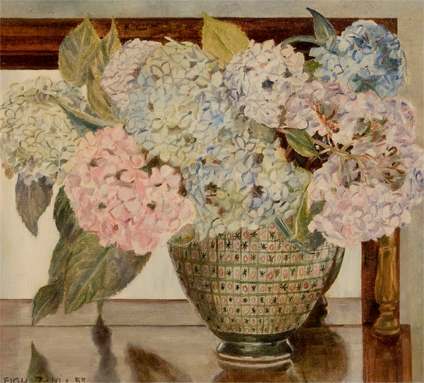 A bouquet of pink, white, and blue hydrangeas  in a patterned vase on a polished surface. The bouquet's reflection is partially seen in the mirror with a rectangular frame behind them.