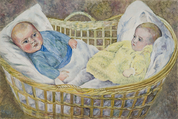 Twin babies, Max and Suzi Irving in a large wicker basket lay in a white blanket. Max, left, wears a blue cardigan, and Suzi, right, wears a fluffy yellow dress.